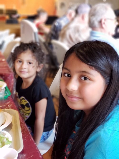 Two young girls smiling with free hot meals at the switchpoint community resource center soup kitchen